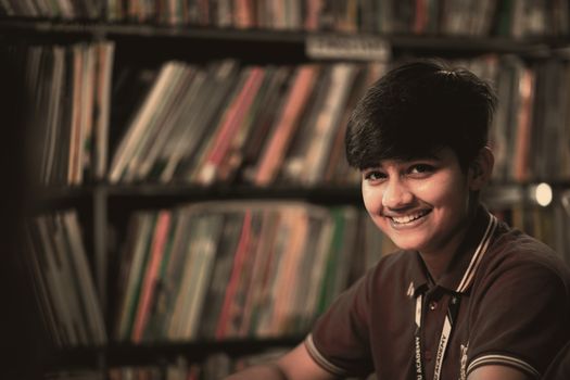 Joyful teenager smiling in a library, creating a warm academic atmosphere.