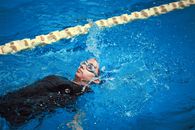 A female swimmer doing a backstroke in a clear blue swimming pool. Perfect for sports and lifestyle themes.