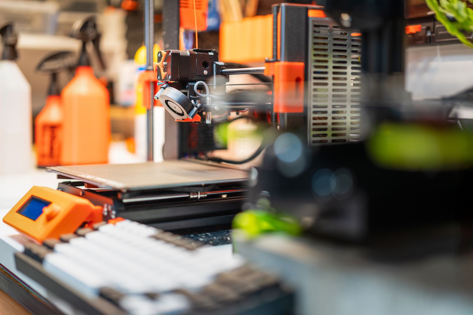 Detailed view of a desktop 3D printer in a busy workshop