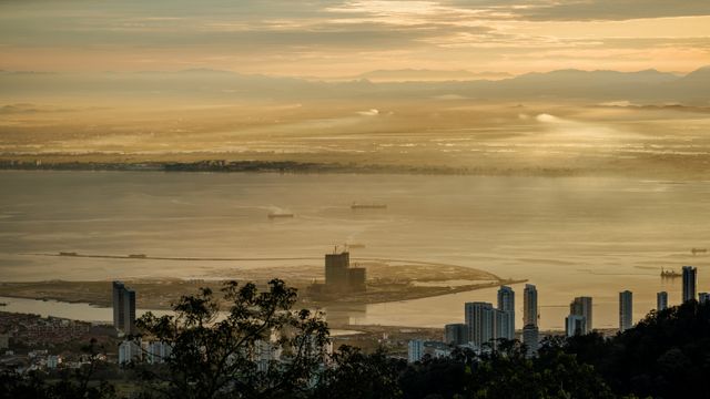 Stunning sunrise view over Penang from Bukit Bendera, Malaysia featuring skyscrapers and the coastline. — lounges at Penang Airport