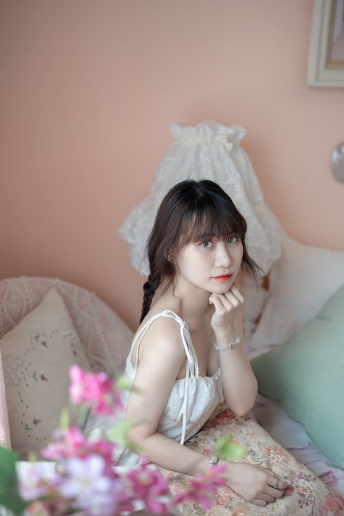 Free A woman in a pastel-themed bedroom with soft lighting and floral decor, creating a peaceful ambiance. Stock Photo
