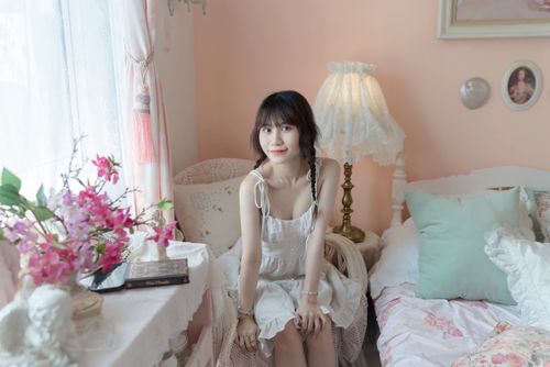 Free Young woman in vintage-style bedroom with soft natural lighting and decor. Stock Photo