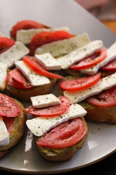 Close-up of appetizer with tomato and brie on toast garnished with herbs.