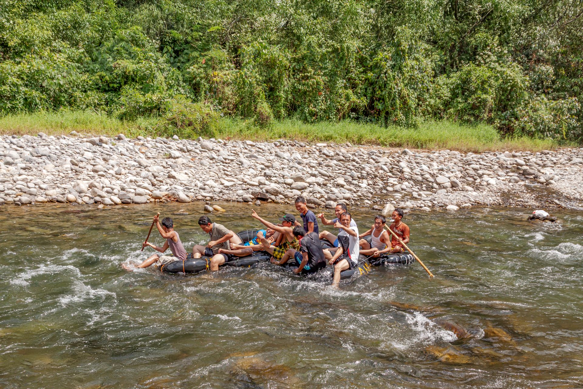 Group of people enjoying a thrilling river rafting experience on a sunny day.