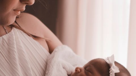 Tender moment of a mother holding her newborn child by a window, capturing love and warmth.