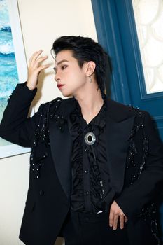 Stylish adult posing in a black outfit indoors, exuding elegance.