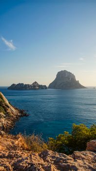 Stunning landscape of Es Vedrà island off Ibiza's coast during sunset, capturing vibrant blues and rocky cliffs.