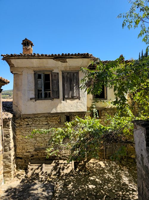 Free Charming dilapidated stone house with weathered windows under a bright blue sky. Stock Photo