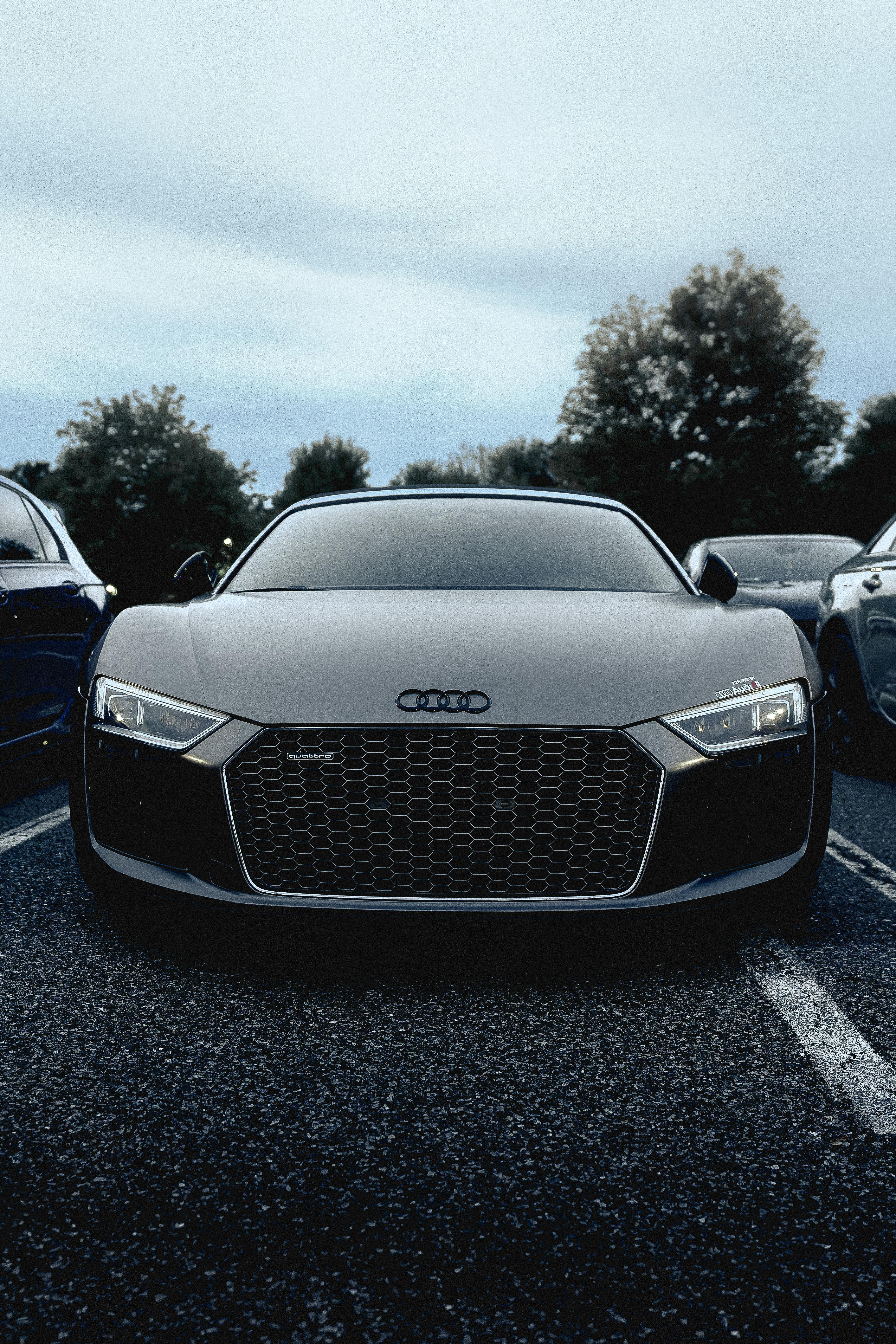 Free A modern Audi R8 car is prominently displayed in an outdoor parking lot, showcasing its sleek design. Stock Photo