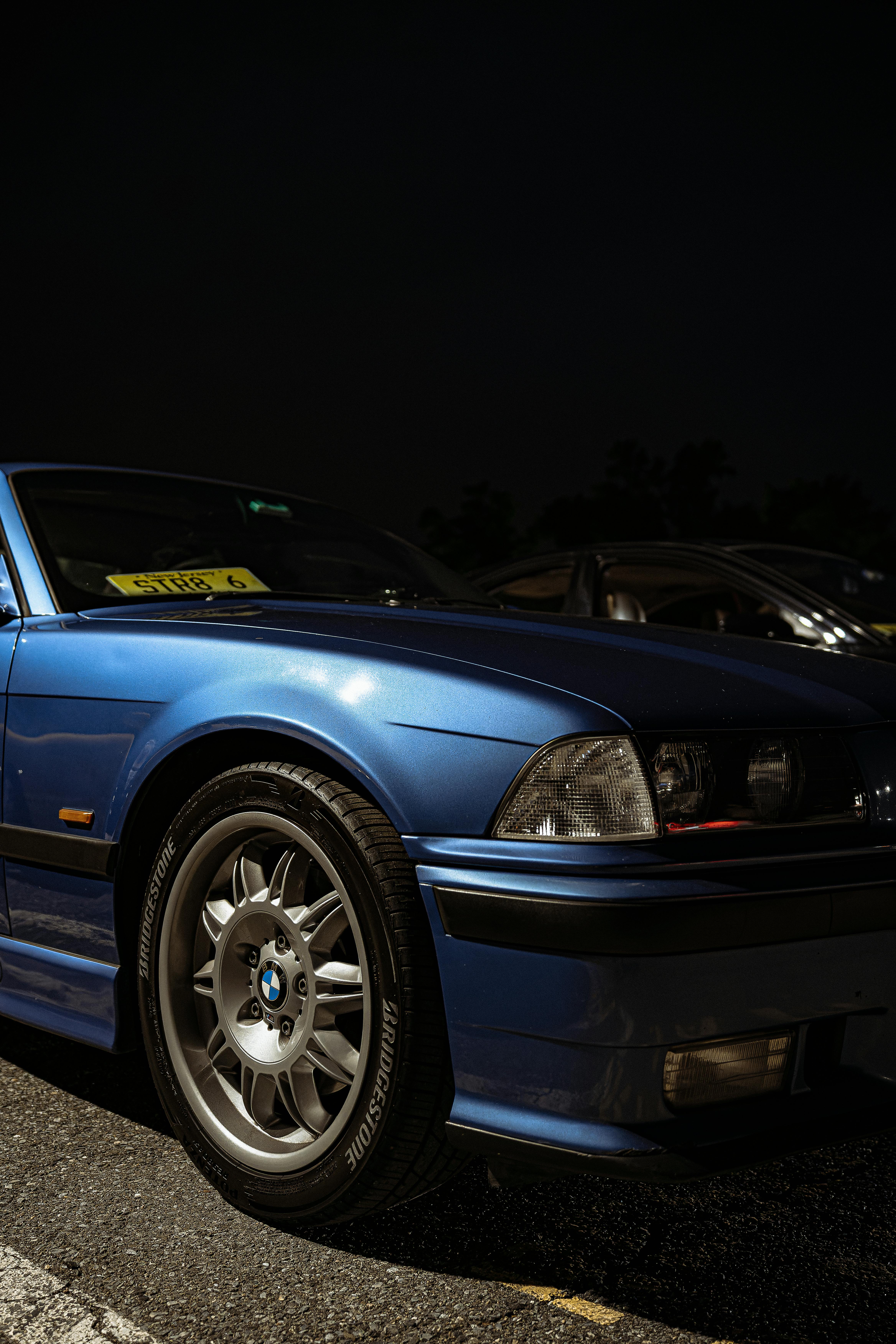 A striking blue BMW E36 parked at night, showcasing sleek design and classic lines.