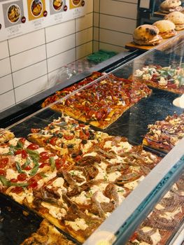 Freshly baked Italian pizzas on display in a traditional pizzeria in Rome, Italy.