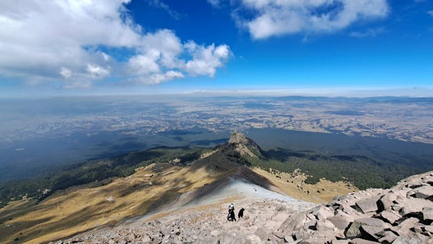 A breathtaking view from a mountain top with hikers ascending the peak.