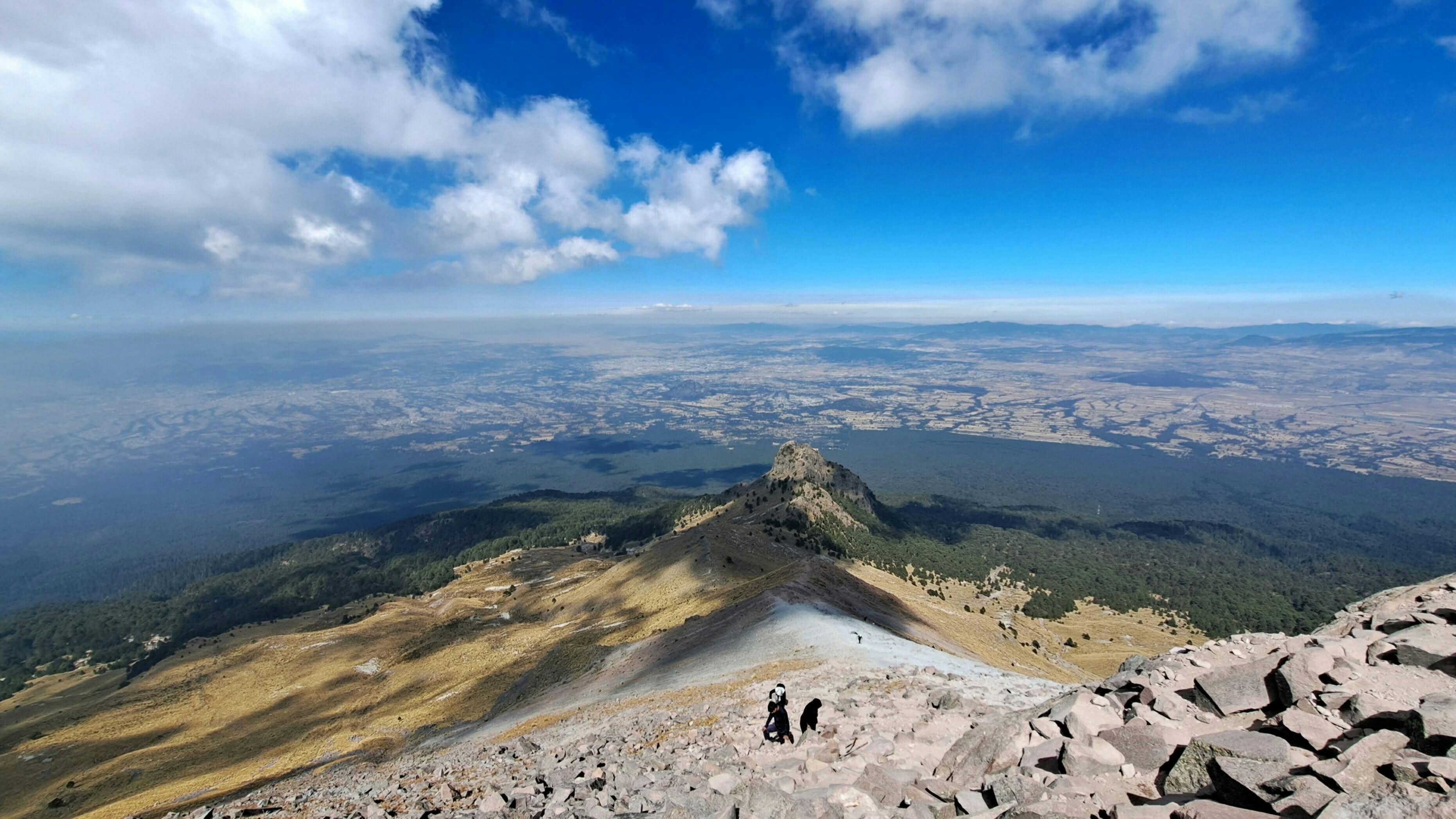 Gratis Una vista mozzafiato dalla cima di una montagna con escursionisti che salgono sulla vetta. Foto a disposizione