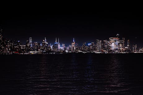 Breathtaking night view of the illuminated New York City skyline across the water.