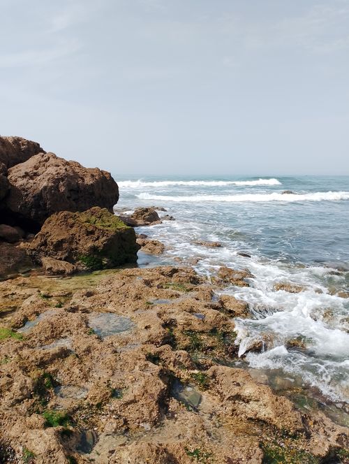 Free A beautiful summer day at Casablanca's rocky beach with waves crashing gently. Stock Photo