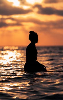 A serene silhouette of a woman standing in the water at sunset in Tel Aviv, Israel.