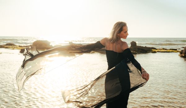 Woman in a flowing black dress dancing at sunset