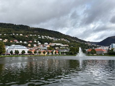 Picturesque view of Bergen, Norway with colorful houses, a fountain, and mountains.