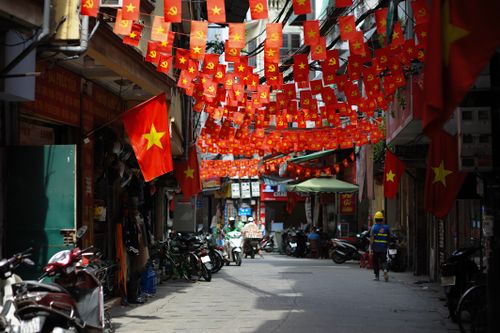 Free A lively street in Hanoi adorned with numerous Vietnamese flags, capturing local culture. Stock Photo