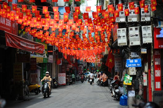 Street scene with vibrant red flags and people on motorcycles, creating a festive and lively atmosphere.