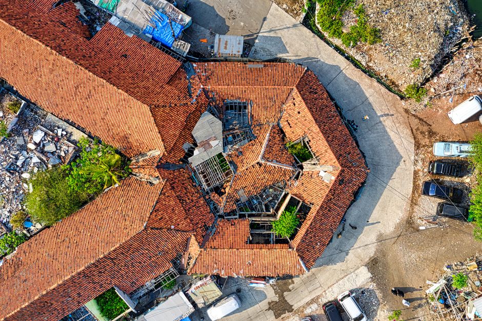 Aerial drone shot capturing a rooftop in Jakarta, showcasing unique architectural design with fallen debris around.