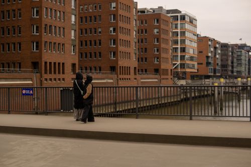 Free A couple standing by the river in Hamburg with brick architecture. Stock Photo