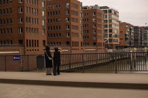 Free Two people viewing HafenCity's distinctive architecture in Hamburg, Germany, during a cloudy day. Stock Photo