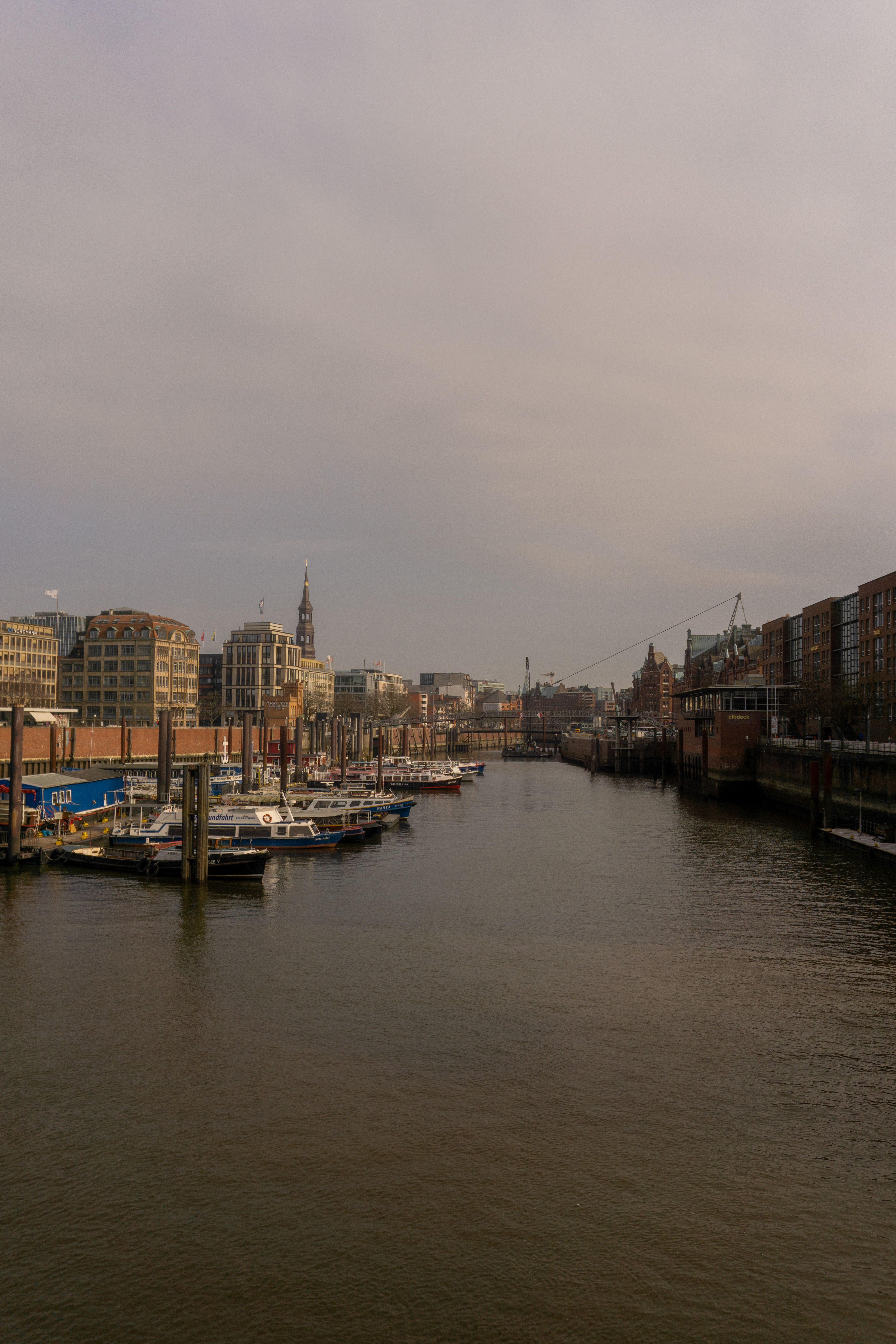 Explore the picturesque landscape of Hamburg's iconic harbor with historic buildings and moored boats.