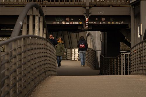 Free People walking under a Hamburg walkway bridge, capturing urban daily life. Stock Photo