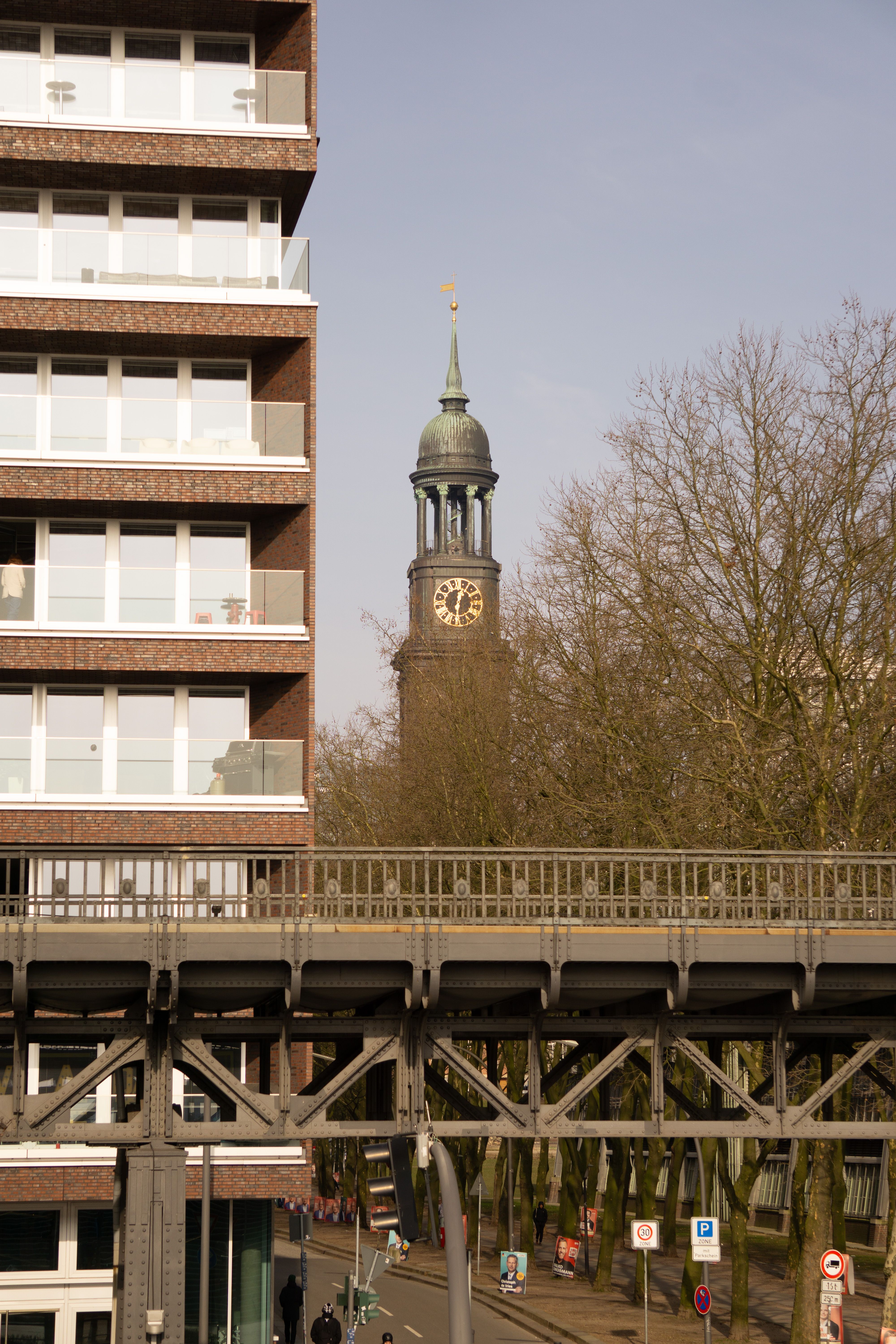 Clock tower of St. Michael's Church viewed from urban street with modern architecture in Hamburg.