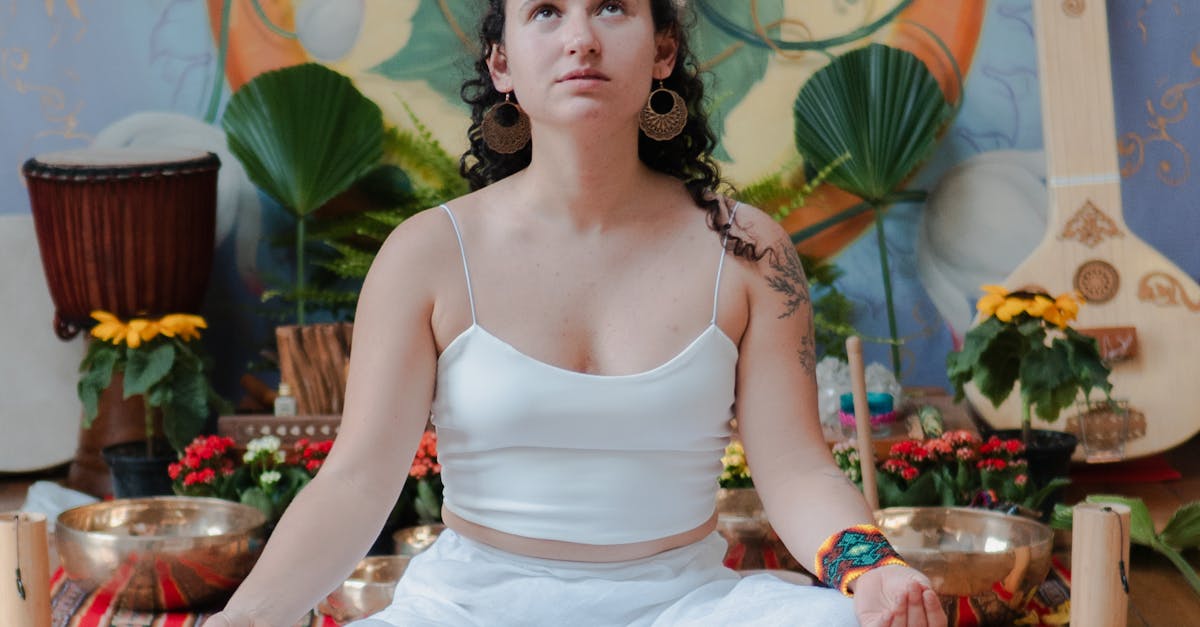 Woman meditating indoors with a peaceful floral and spiritual backdrop.