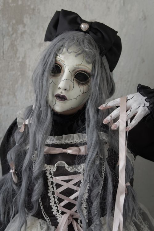 Free A person dressed as a creepy doll with a cracked porcelain mask and lace costume. Stock Photo