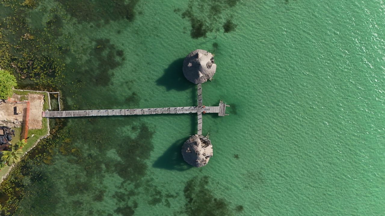 Aerial view of a wooden pier extending to two round platforms in green water