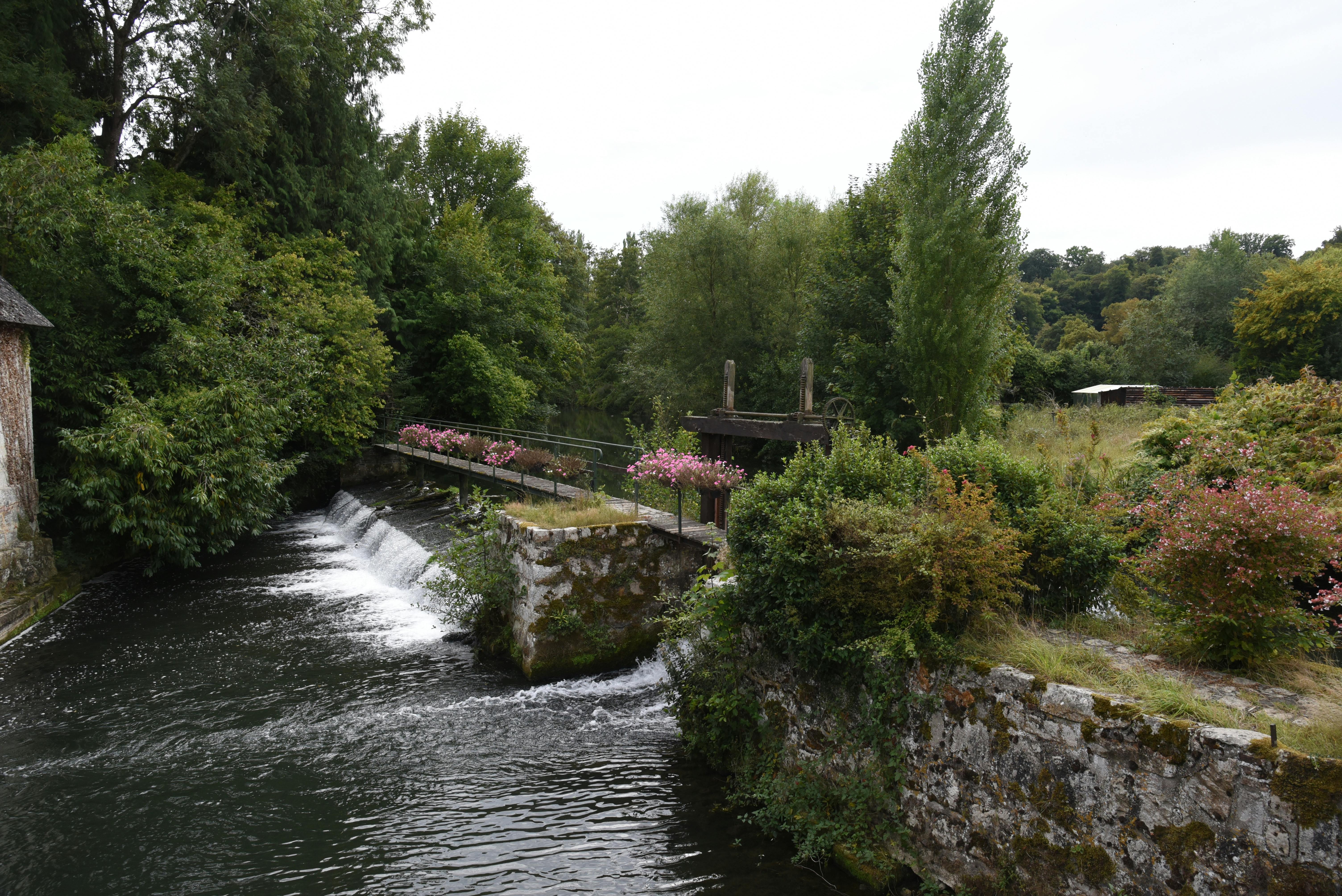Scenic view of a peaceful watermill surrounded by lush greenery in Broglie, Normandy, France.