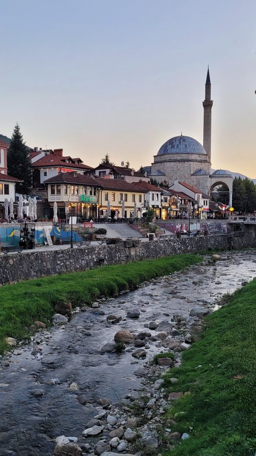 Free A scenic view of a riverbank with a historic mosque and charming town at sunset. Stock Photo