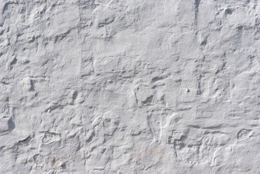 Detailed close-up of a textured white plaster wall showcasing its intricate surface patterns.