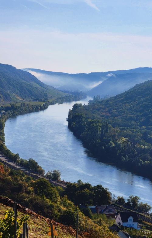 Free A picturesque view of a winding river surrounded by lush green hills under a clear blue sky. Stock Photo