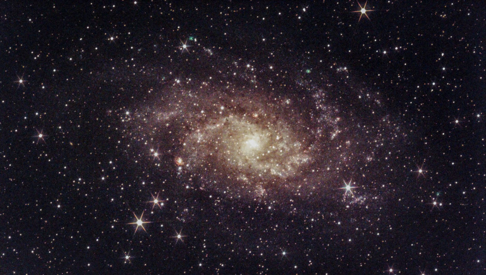Bright spiral galaxy surrounded by stars in deep space.