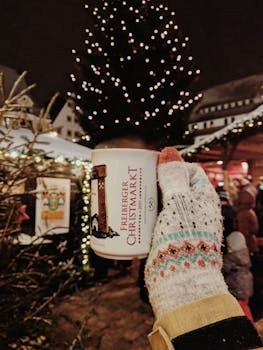 在神奇的弗赖伯格圣诞市场，一只戴着手套的手正拿着马克杯