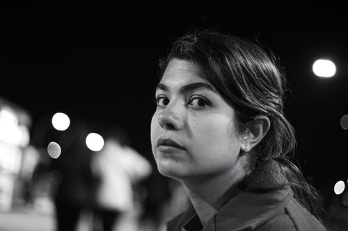 Free A captivating black and white portrait of a woman lit by street lights at night with a bokeh background. Stock Photo