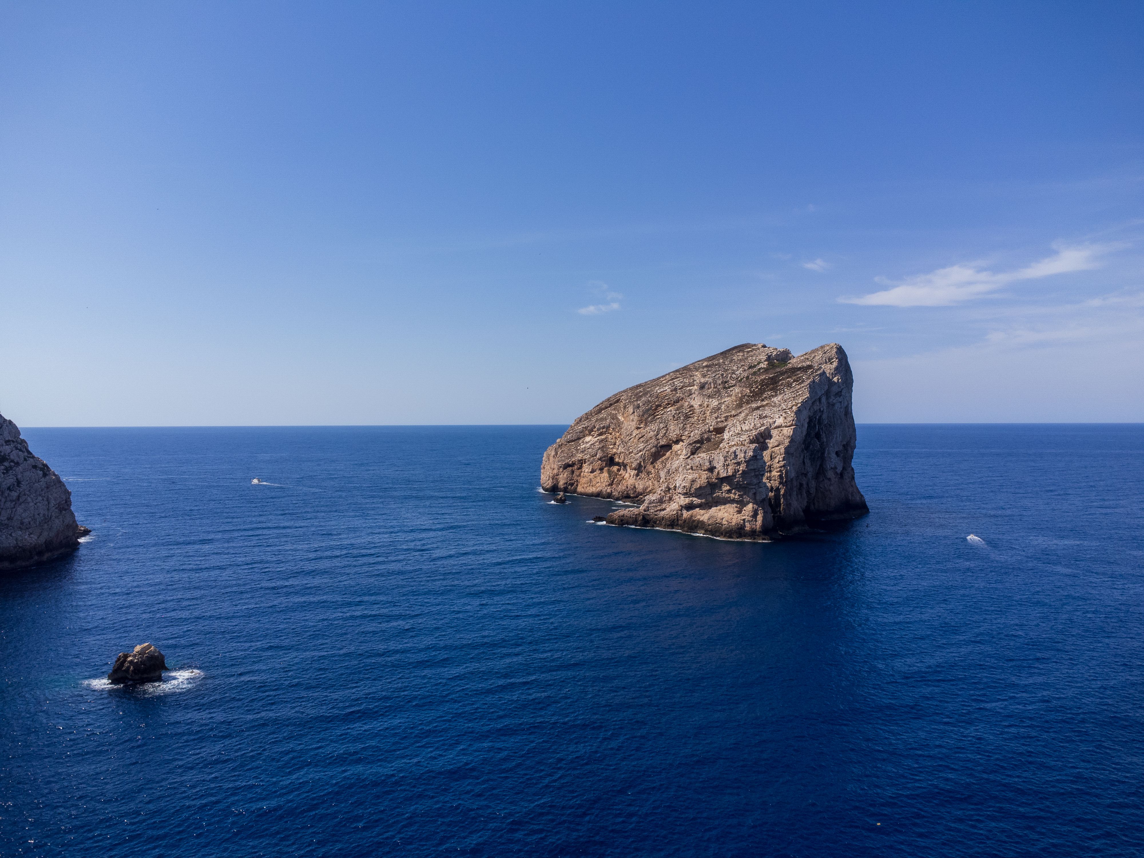 Aerial view of a striking rock island amidst the deep blue waters of Sardinia, Italy.