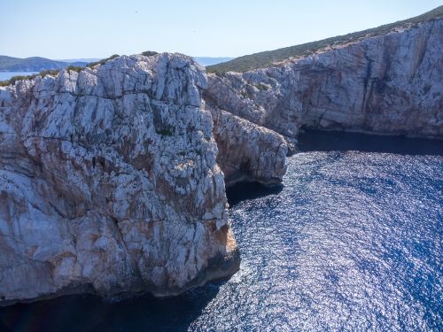 Free Stunning aerial view of the rugged cliffs and shimmering blue waters of Sardinia, Italy. Stock Photo
