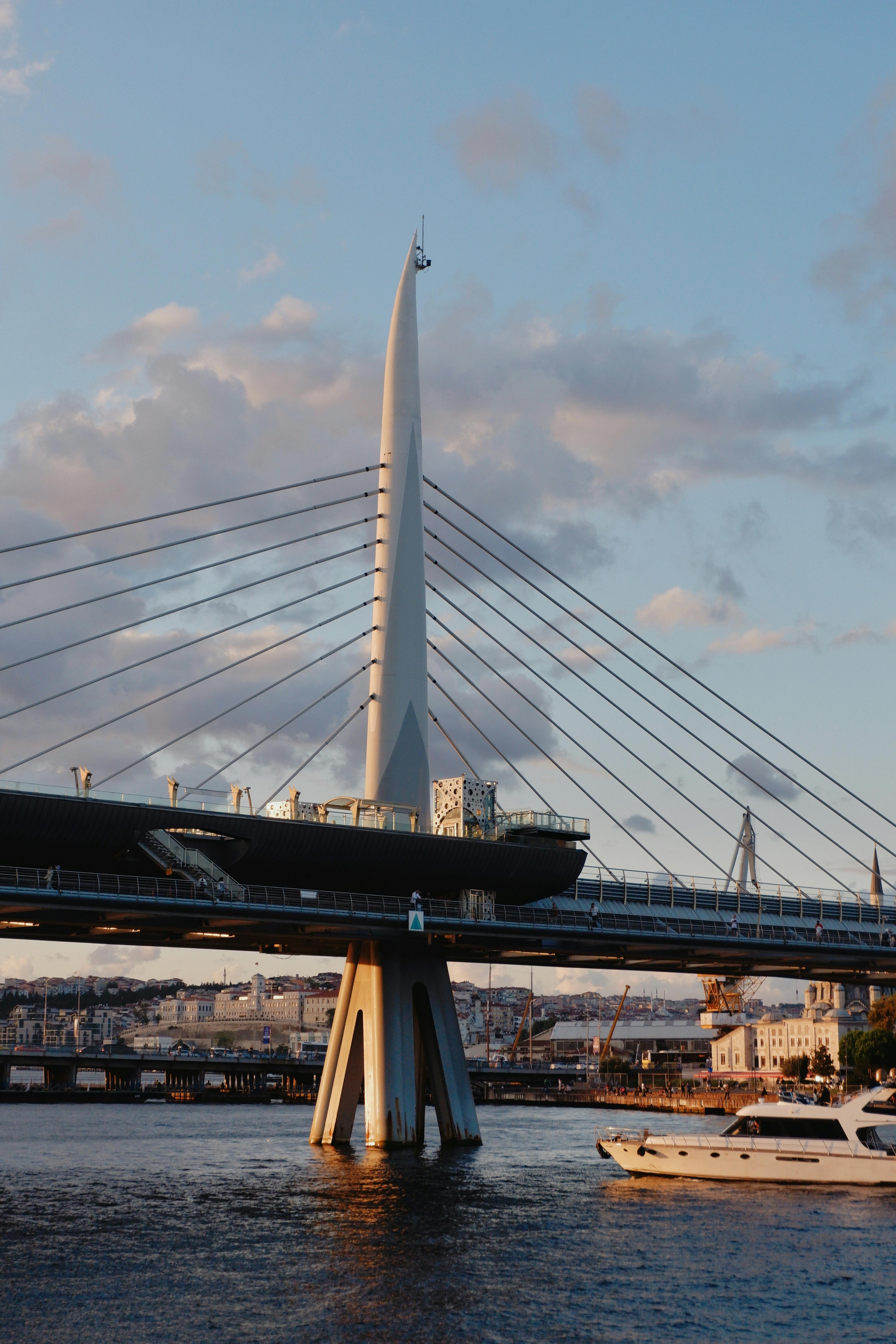 Stunning view of a modern cable-stayed bridge at sunset with a boat passing below.