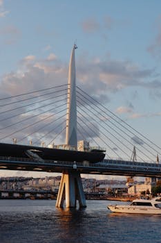 Stunning view of a modern cable-stayed bridge at sunset with a boat passing below.