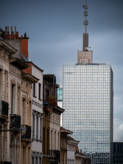 Free Stunning view of a modern skyscraper contrasting with historic city architecture, under a moody sky. Stock Photo