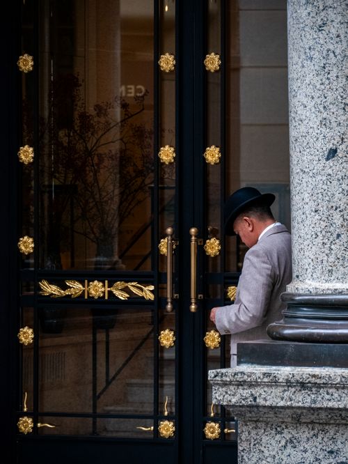 Free Elegant entrance with a man in classic attire and a hat, highlighting architectural details. Stock Photo