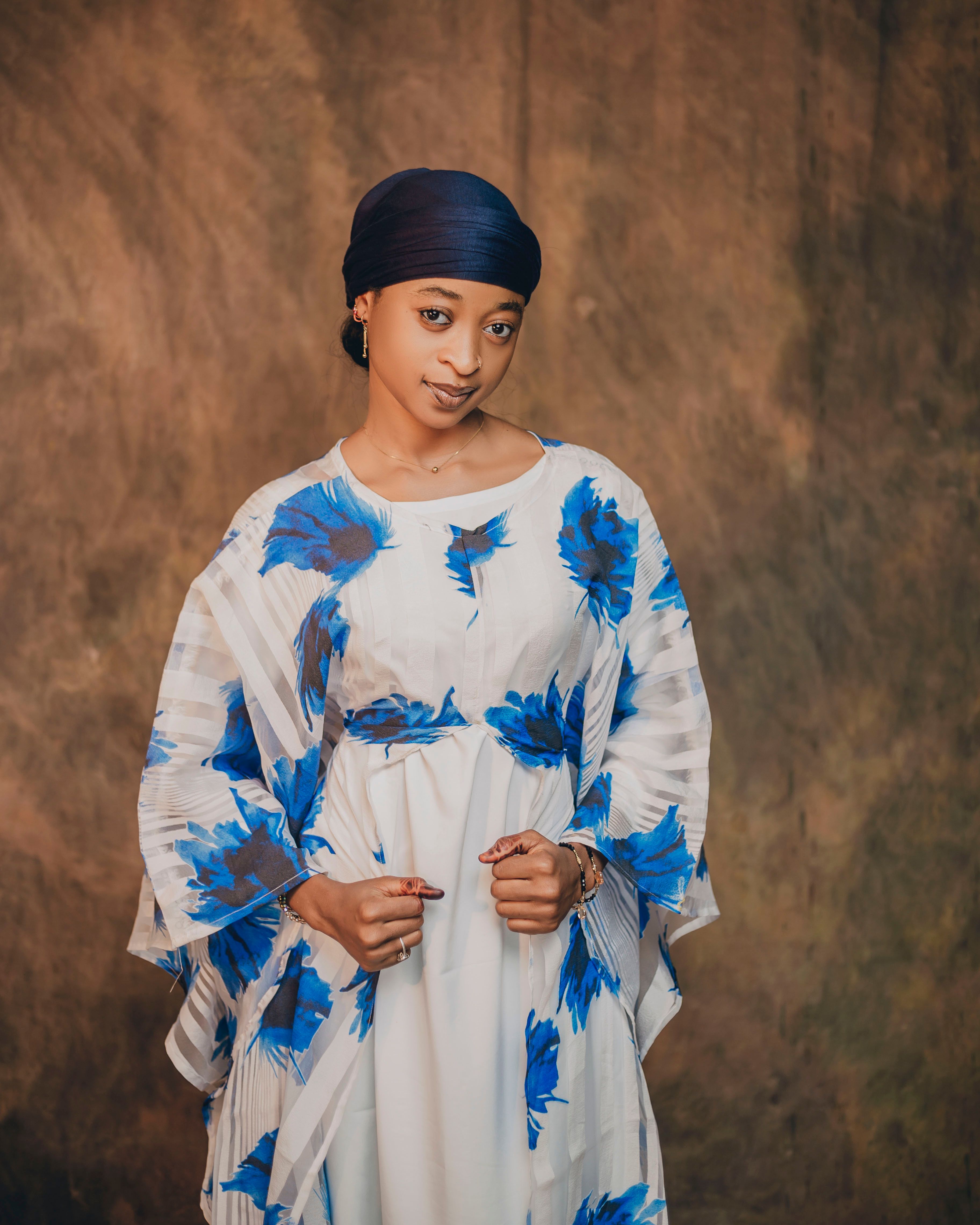 Portrait of a woman wearing blue floral dress with brown backdrop.