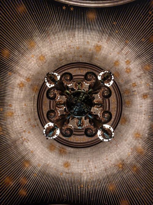 Free Chandelier with star motif shines from an opulent ceiling. Stock Photo