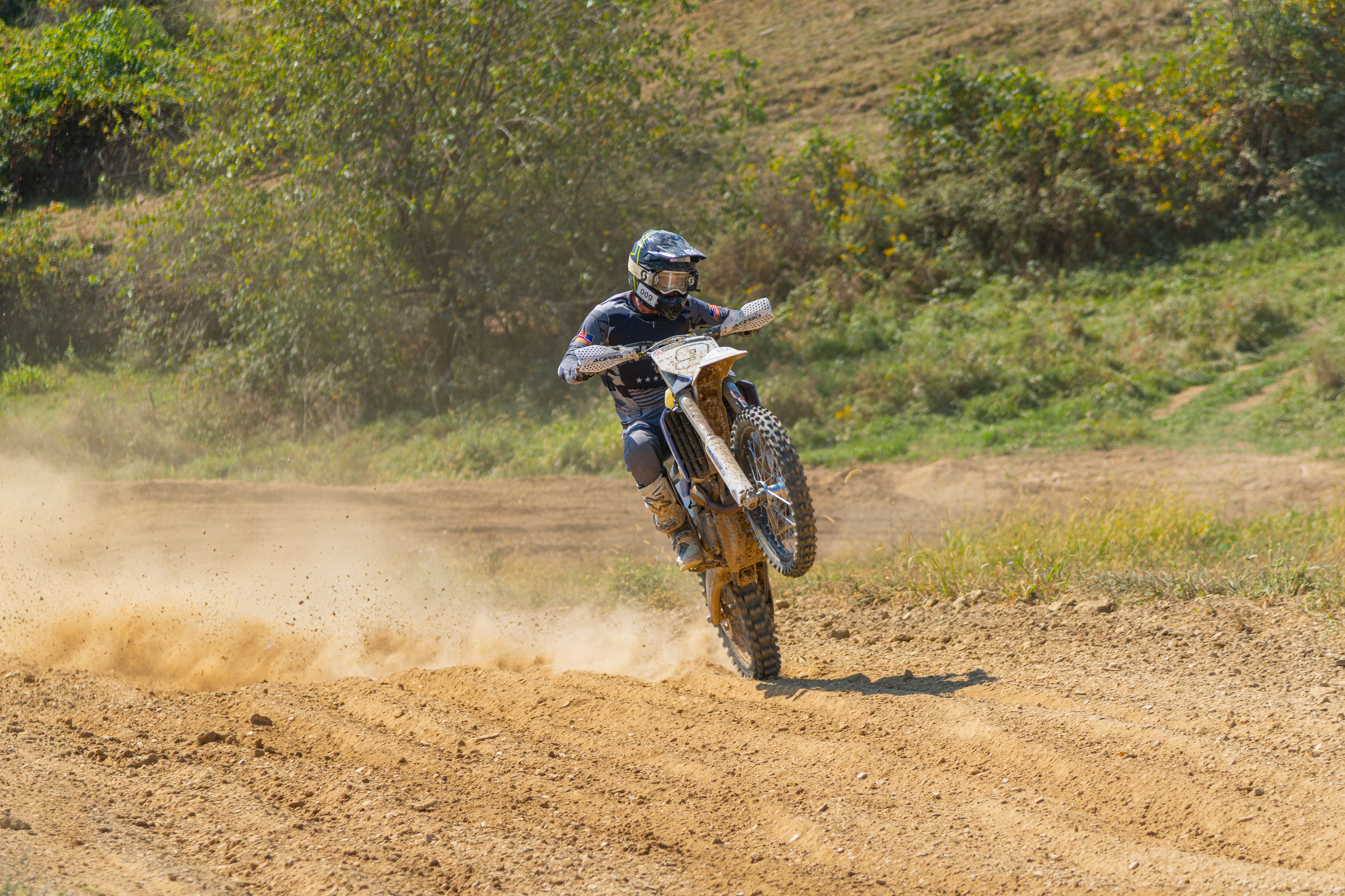 Motocross rider performing a wheelie on a dirt track.