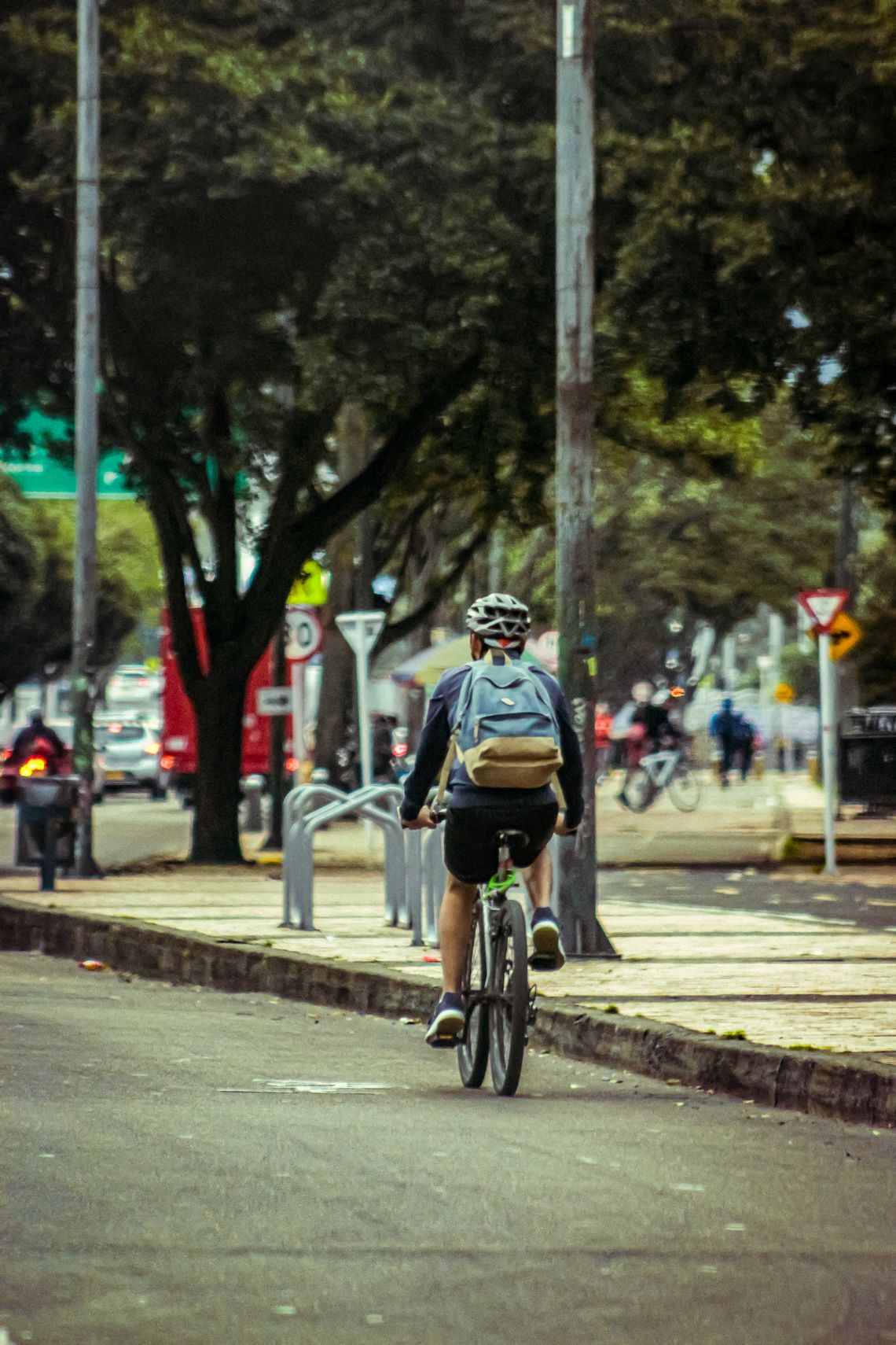 Urban cyclist riding through a green city street